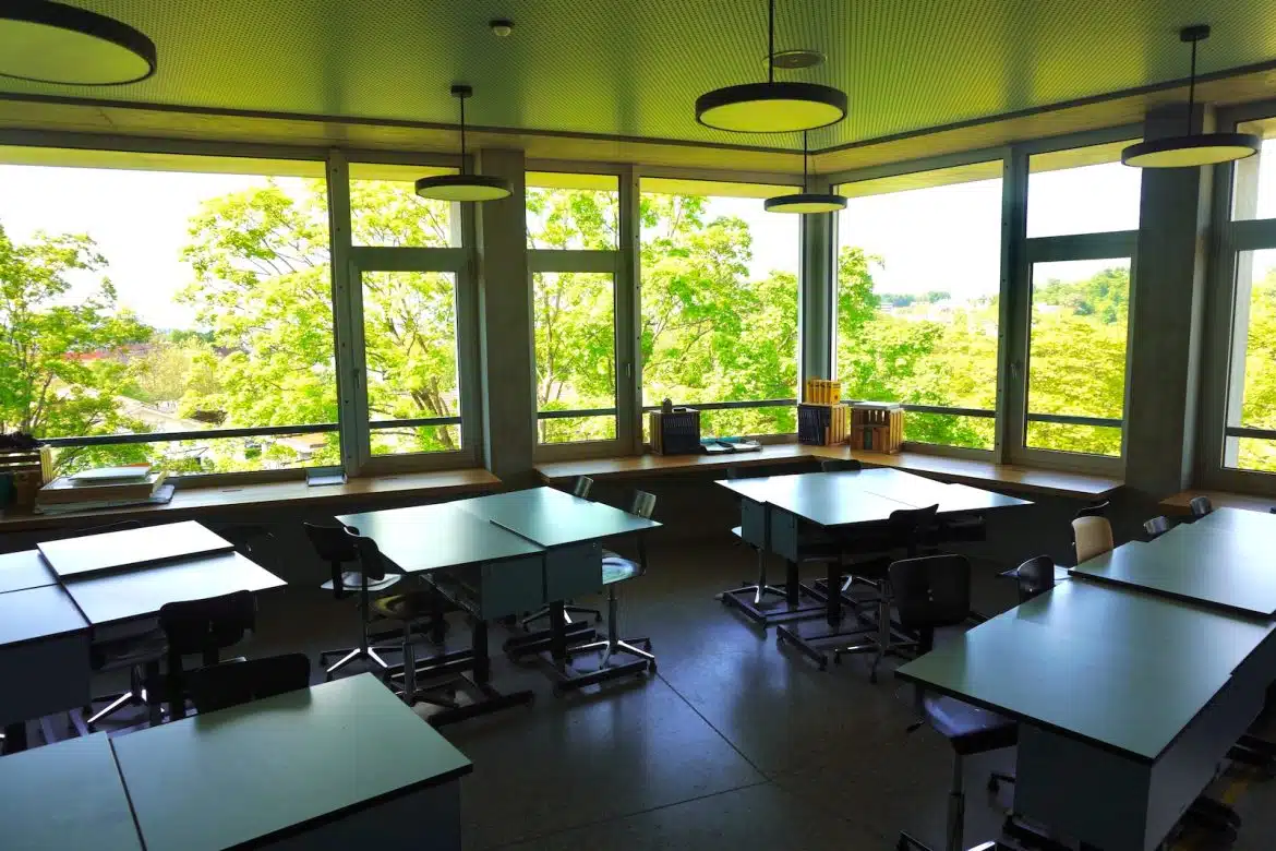 an empty classroom with desks and windows